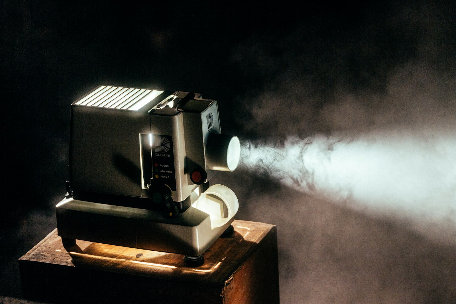 A projector in a dark room throwing a hard beam of light through the haze.